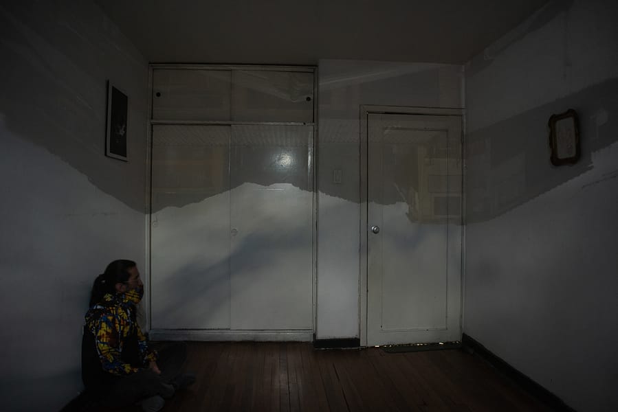 hombre sentado en el piso viendo una proyección de cára oscura